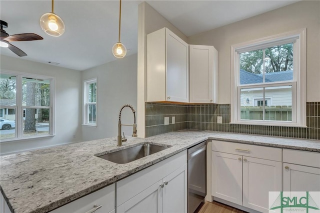 kitchen featuring sink, light stone counters, dishwasher, pendant lighting, and white cabinets