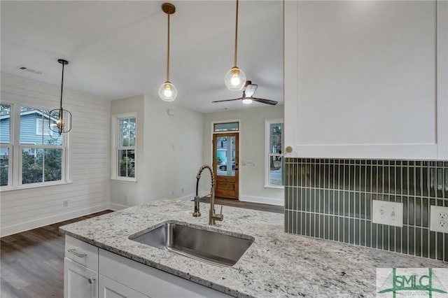 kitchen featuring light stone counters, sink, decorative light fixtures, and white cabinets