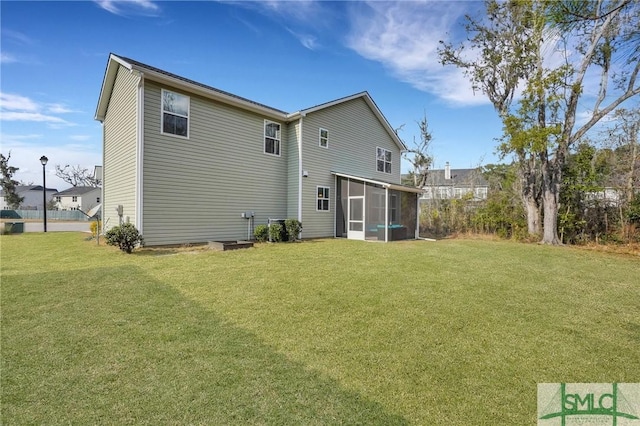 rear view of house featuring a sunroom and a lawn