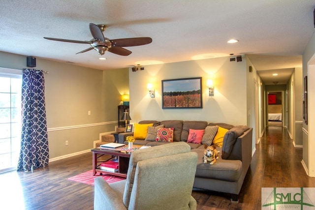 living room featuring ceiling fan, a textured ceiling, and dark hardwood / wood-style flooring