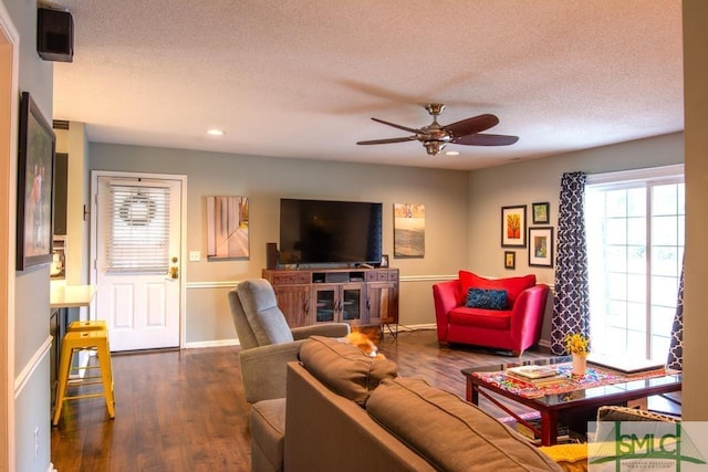 living room with dark wood-type flooring, ceiling fan, and a textured ceiling