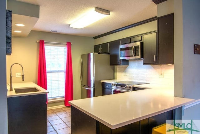 kitchen featuring sink, appliances with stainless steel finishes, backsplash, a kitchen breakfast bar, and kitchen peninsula