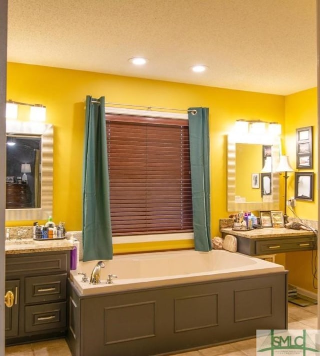 bathroom with tile patterned flooring, vanity, a washtub, and a textured ceiling