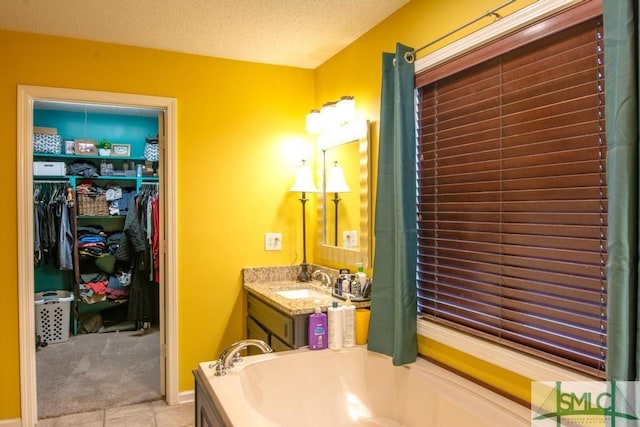 bathroom featuring a washtub, vanity, tile patterned flooring, and a textured ceiling