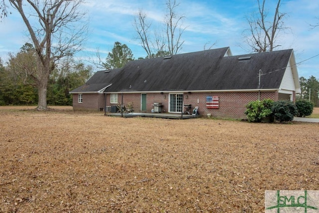 rear view of house with a wooden deck, central AC unit, and a lawn