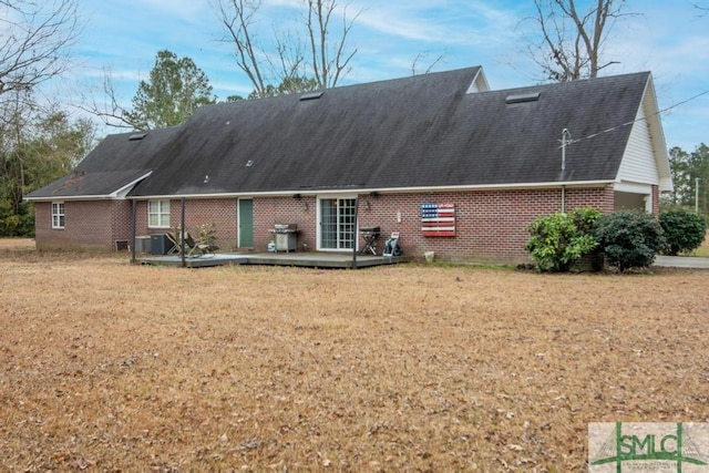 rear view of property with a wooden deck, a yard, and central air condition unit