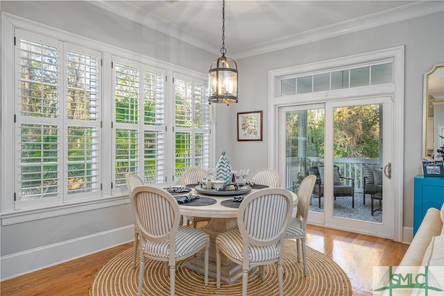 dining room with an inviting chandelier, ornamental molding, and light hardwood / wood-style flooring