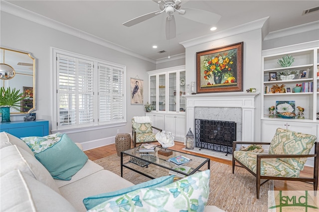 living room with a premium fireplace, crown molding, ceiling fan, and light hardwood / wood-style floors