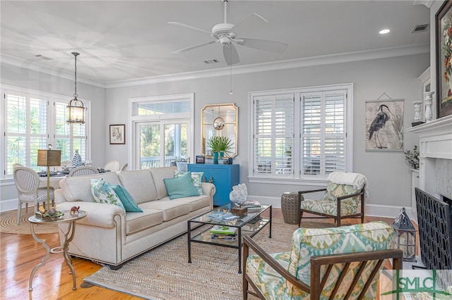 living room featuring crown molding, light hardwood / wood-style flooring, and ceiling fan with notable chandelier