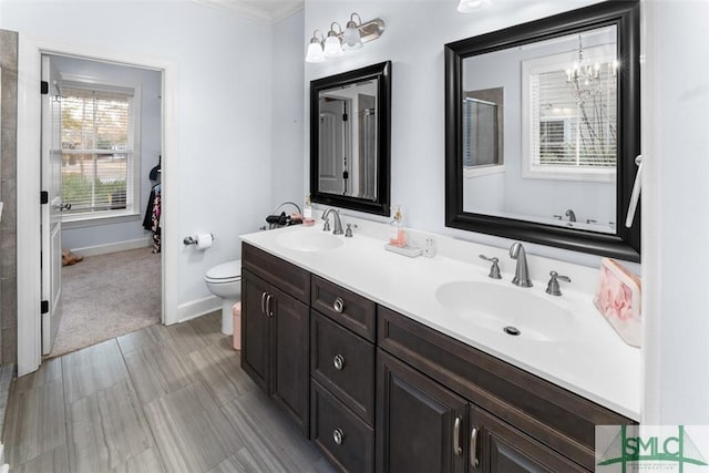 bathroom with crown molding, vanity, toilet, and an inviting chandelier