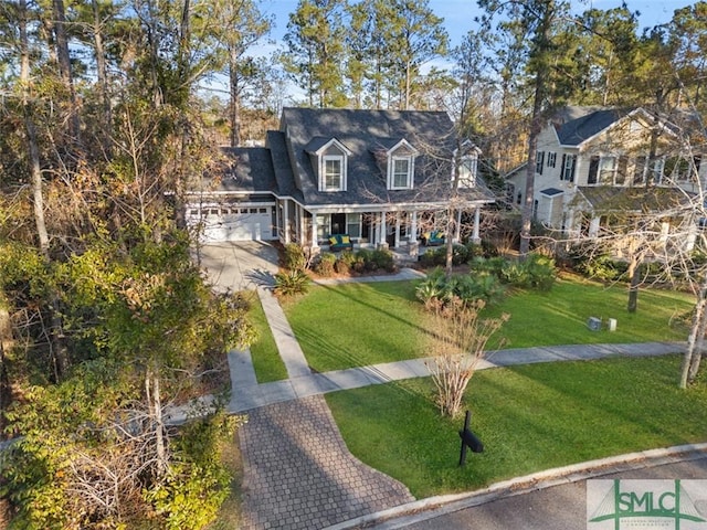 new england style home featuring a garage, a front yard, and covered porch