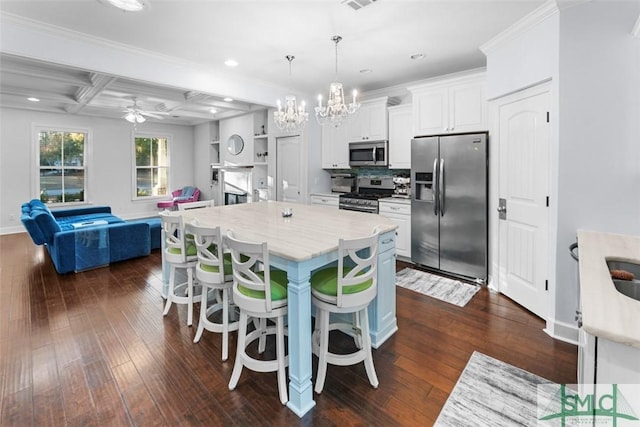 kitchen with a breakfast bar, white cabinetry, decorative light fixtures, appliances with stainless steel finishes, and a kitchen island