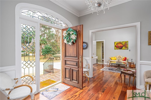 foyer with an inviting chandelier, hardwood / wood-style floors, and crown molding