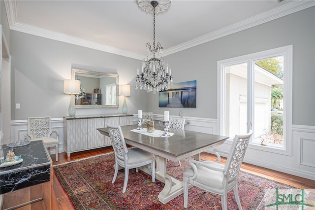 dining area with crown molding, wood-type flooring, and an inviting chandelier