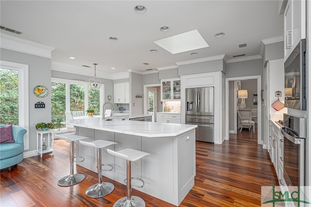 kitchen featuring stainless steel appliances, white cabinetry, sink, and a large island with sink