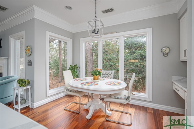 dining area featuring hardwood / wood-style flooring, a wealth of natural light, ornamental molding, and a chandelier