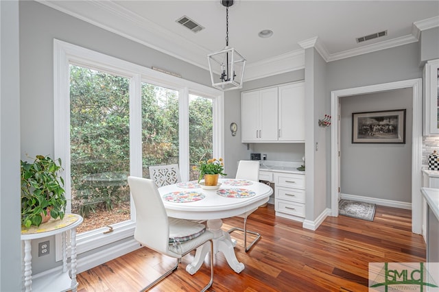 dining space featuring ornamental molding, a wealth of natural light, built in desk, and dark hardwood / wood-style flooring