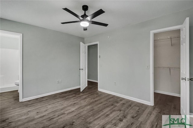 unfurnished bedroom with connected bathroom, a spacious closet, dark hardwood / wood-style floors, and a closet