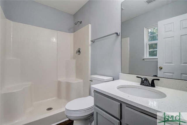 bathroom featuring vanity, toilet, and a shower