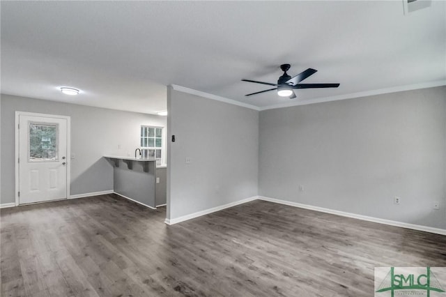 unfurnished living room featuring sink, crown molding, dark hardwood / wood-style floors, and ceiling fan