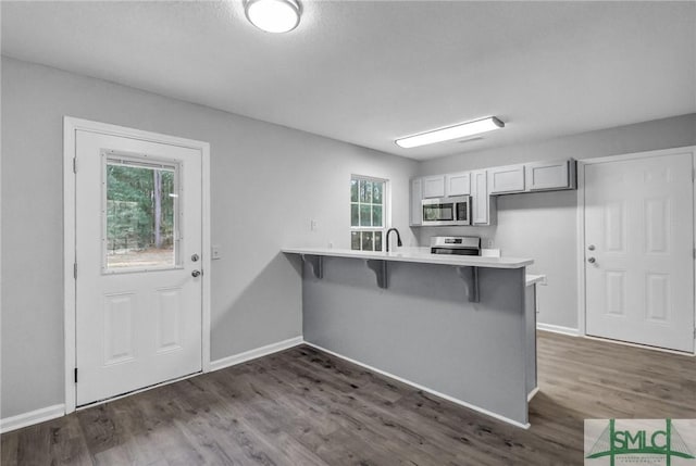 kitchen with a breakfast bar, white cabinetry, dark hardwood / wood-style flooring, range, and kitchen peninsula