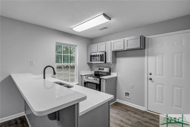 kitchen featuring stainless steel appliances, kitchen peninsula, sink, and gray cabinetry