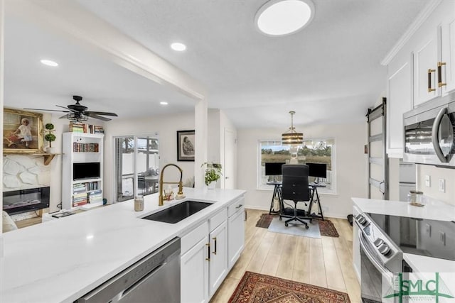 kitchen with sink, appliances with stainless steel finishes, pendant lighting, a barn door, and white cabinets