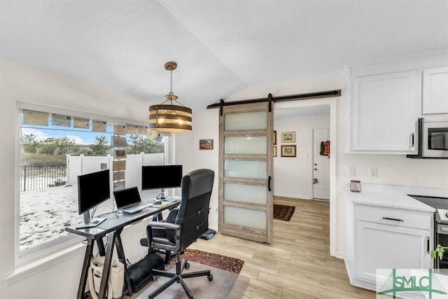 office area with a barn door, lofted ceiling, and light hardwood / wood-style floors