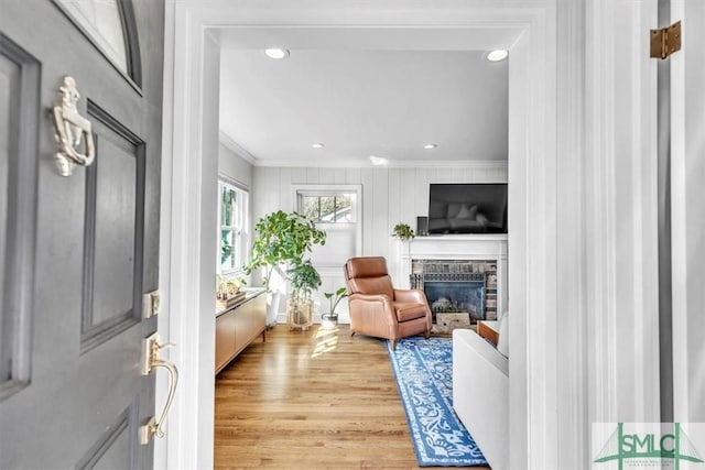 interior space with ornamental molding, a brick fireplace, and light hardwood / wood-style flooring