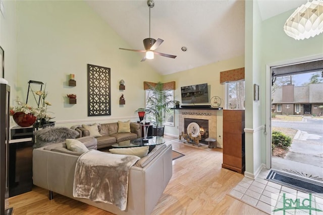 living room featuring ceiling fan, a fireplace, high vaulted ceiling, and light hardwood / wood-style flooring