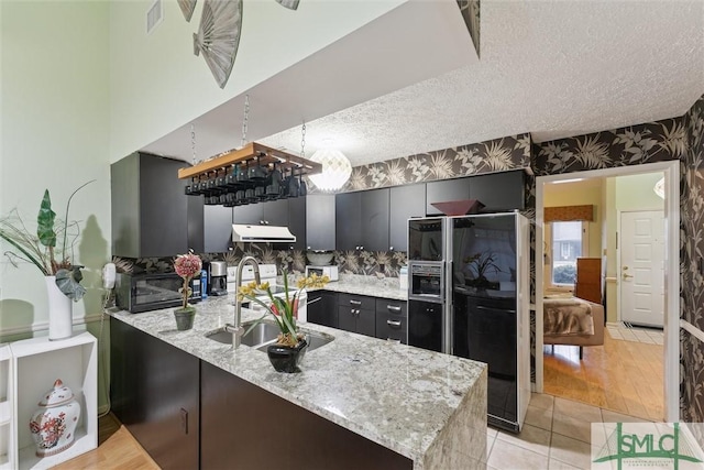 kitchen with sink, black fridge with ice dispenser, kitchen peninsula, and a textured ceiling