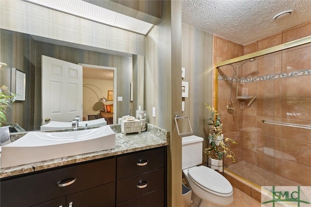 bathroom featuring vanity, a shower with shower door, toilet, and a textured ceiling