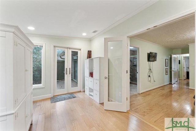 entrance foyer featuring french doors, crown molding, and light hardwood / wood-style floors