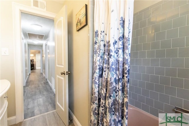 bathroom with toilet, shower / bathtub combination with curtain, and hardwood / wood-style floors