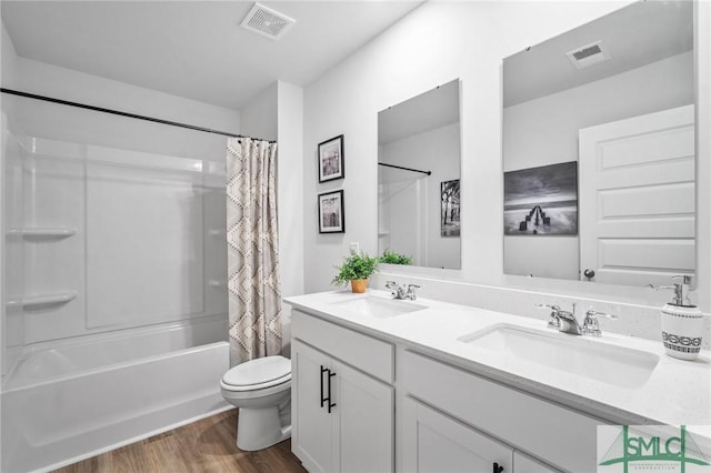 full bathroom with hardwood / wood-style flooring, shower / bath combo, vanity, and toilet