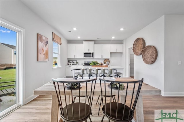 kitchen featuring white cabinetry, appliances with stainless steel finishes, a breakfast bar, and light hardwood / wood-style floors