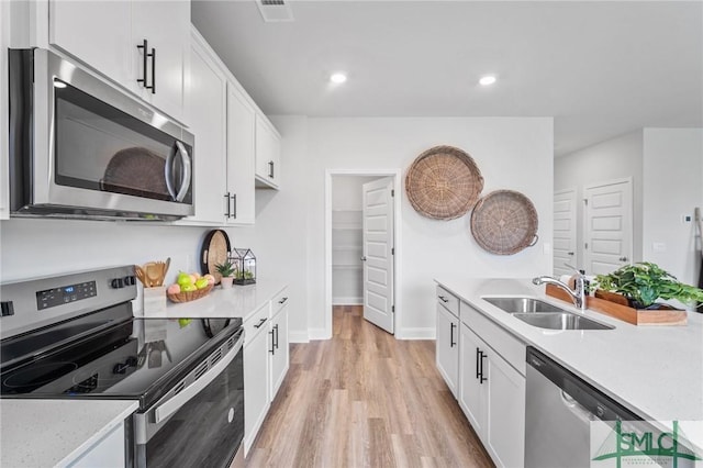 kitchen featuring appliances with stainless steel finishes, sink, white cabinets, and light hardwood / wood-style flooring