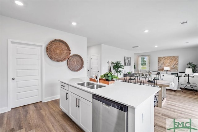 kitchen with sink, an island with sink, white cabinets, stainless steel dishwasher, and light wood-type flooring