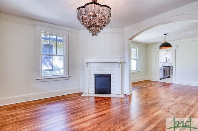 unfurnished living room with a notable chandelier, hardwood / wood-style flooring, and a fireplace