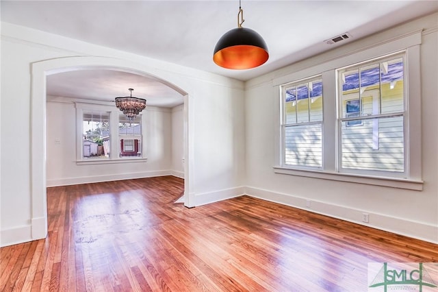 empty room with a chandelier and hardwood / wood-style floors