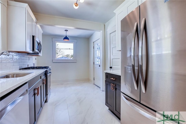 kitchen featuring decorative light fixtures, tasteful backsplash, sink, white cabinets, and stainless steel appliances