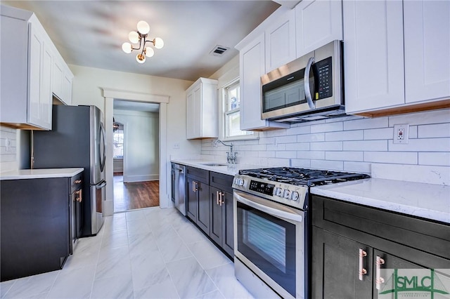 kitchen with stainless steel appliances, a healthy amount of sunlight, sink, and white cabinets