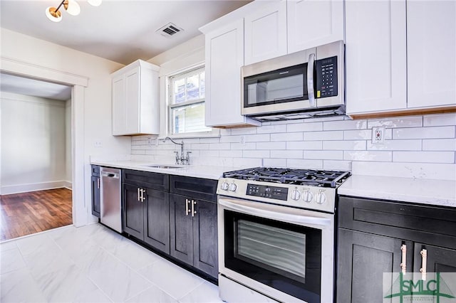 kitchen with sink, backsplash, stainless steel appliances, and white cabinets