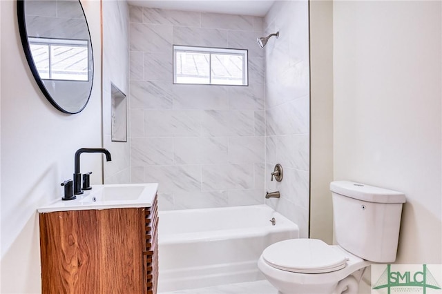 full bathroom featuring tiled shower / bath combo, vanity, and toilet