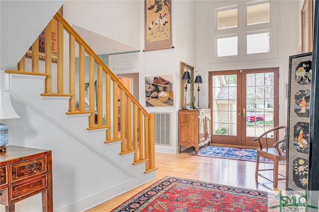 foyer with a towering ceiling, light hardwood / wood-style flooring, and french doors