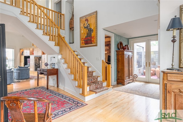 stairs featuring wood-type flooring, a towering ceiling, and french doors