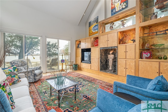 living room featuring a tiled fireplace and high vaulted ceiling