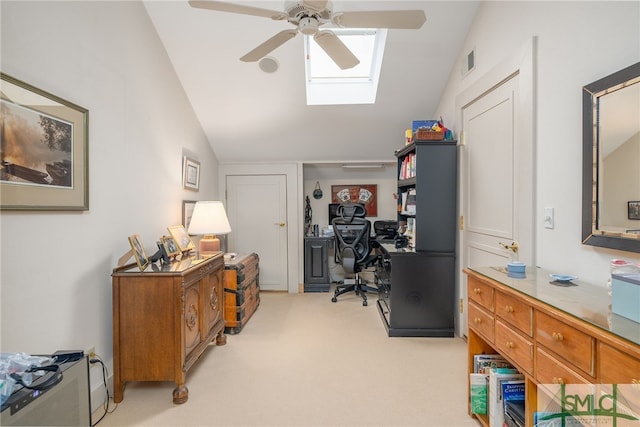 carpeted office space with ceiling fan and vaulted ceiling with skylight