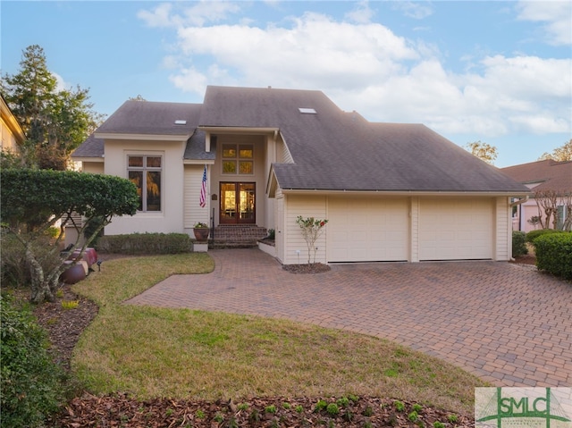 view of front of property with a garage, a front lawn, and french doors