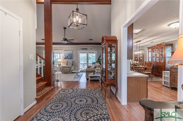 foyer with wood-type flooring, ceiling fan with notable chandelier, and a textured ceiling